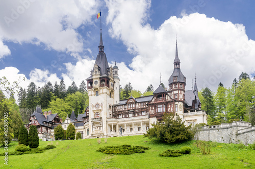 Beautiful view of the famous Peles Castle, Sinaia, Romania, with the Romanian flag flying on top of a spire