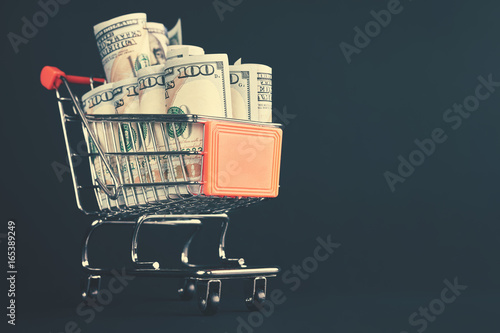 Shopping cart filled with one hundred dollar bill rolls, shallow depth of field, color toning applied.  photo