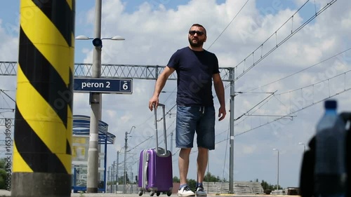 Man walking on the platform and looks irritated while waiting for train
