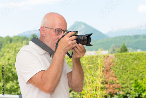  mature man with dslr camera, outdoors