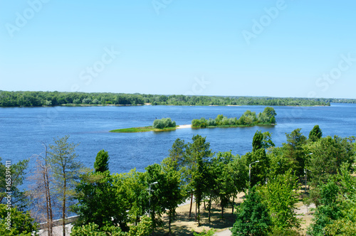 Beautiful landscape on a wide river  with a small island  green banks  with a bird s-eye view. Sunny summer day.