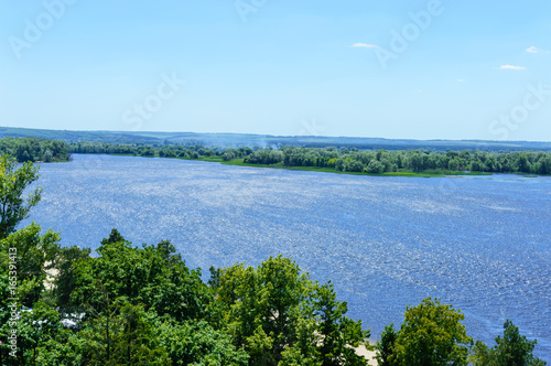 Beautiful landscape on a wide river with a green banks, bird's-eye view. Sunny summer day.
