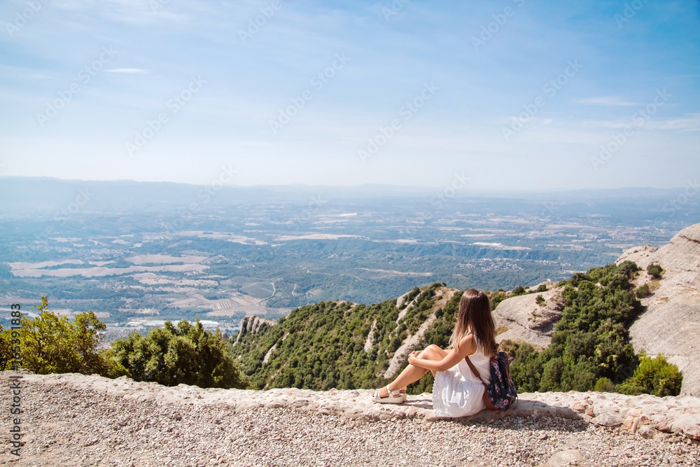 Young woman with backpack enjoying the view in Montserrat mountain on a hot summer day