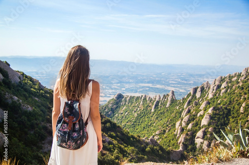 Young woman with backpack enjoying the view in Montserrat mountain on a hot summer day