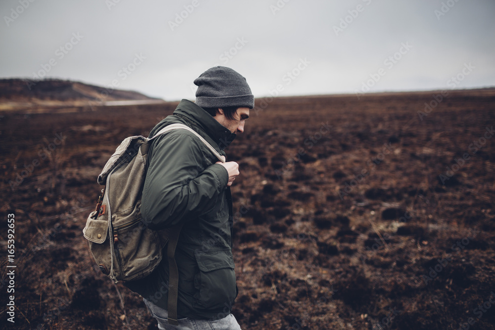 Side view of hiker carrying backpack while walking on barren landscape, Blagoveschensk, Amur, Russia Side view of hiker carrying backpack while walking on barren landscape, Blagoveschensk, Amur, Russia