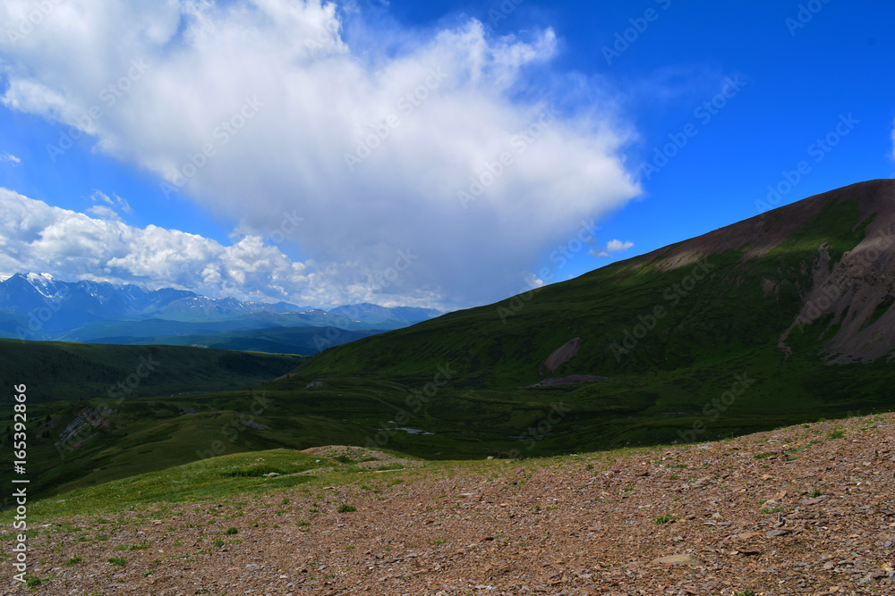 Landscape of green hills and white peaks of North-Chuyski ridge of Altai mountains. Alktash, Altay Republic, Russia.
