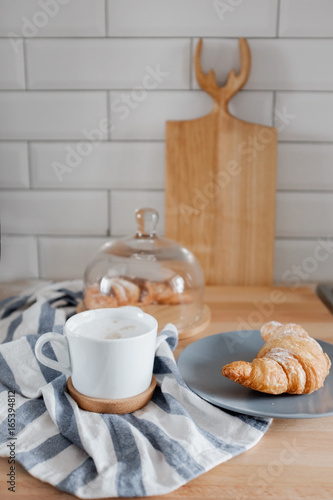 A cup of coffee and a croissant on the table. 
