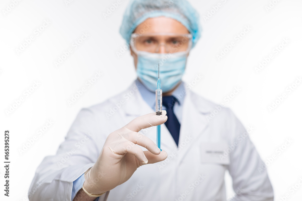 Neat experienced doctor holding a syringe Neat experienced doctor holding a syringe