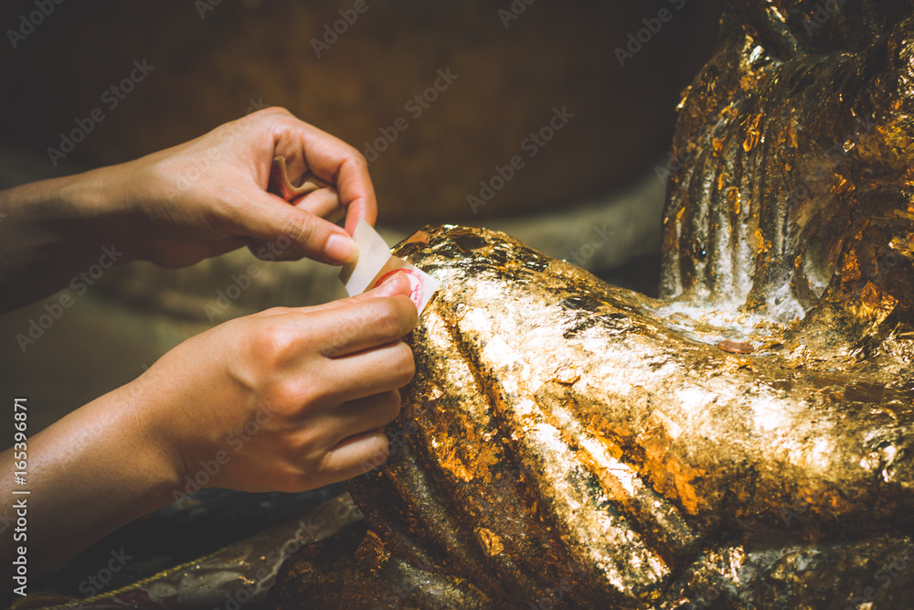 Put gold leaf onto (The Buddha image/ The Buddha statue)/ to gild. Which I use to worship the buddha image