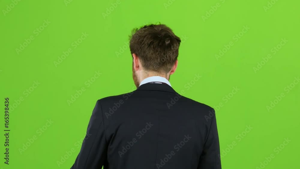 Guy walks down the street, puts his hand in his pocket and waves. Green screen. Back view Guy walks down the street, puts his hand in his pocket and waves. Green screen. Back view