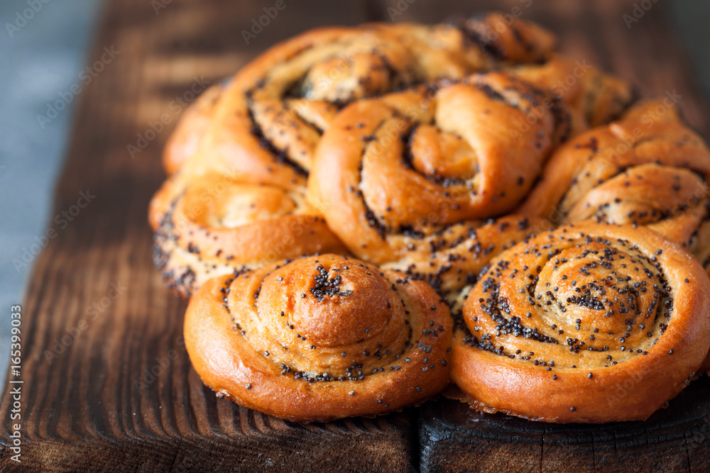 Rolled braided pie with poppy seeds on rustic board close up Rolled braided pie with poppy seeds on rustic board close up