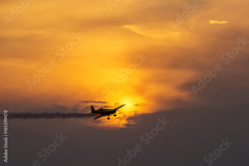 Silhouette of airplane on sunset with smoke in background