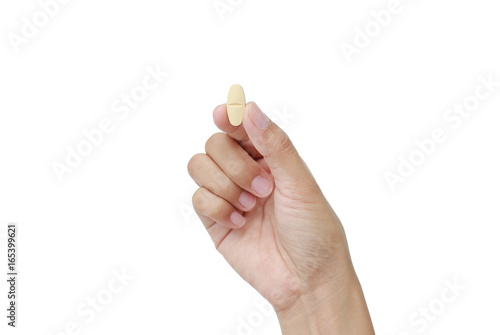 Hand holding yellow pill isolated on white background.