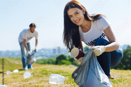 Фотография Motivated admirable woman scavenging litter on a lawn