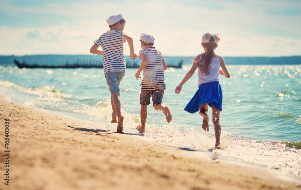 children jumping on the beach in summer hats. Boys and girl having fun at seaside children jumping on the beach in summer hats. Boys and girl having fun at seaside