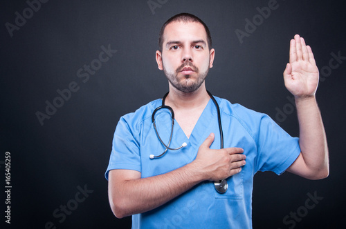Portrait of male doctor with stethoscope taking oath