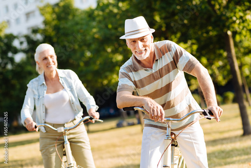 Positive elderly people riding bicycles in park