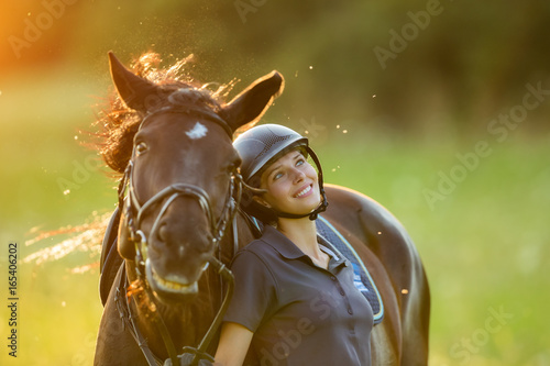Young woman rider with her horse enjoying good mood