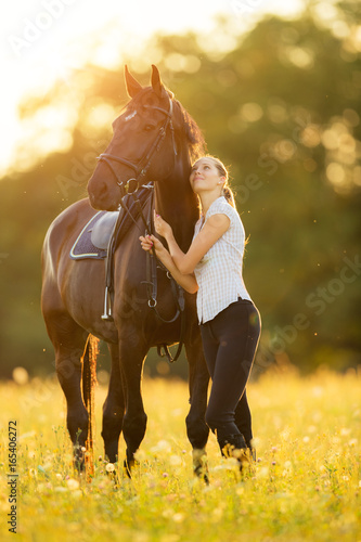 Młoda kobieta z koniem w wieczór zmierzchu świetle