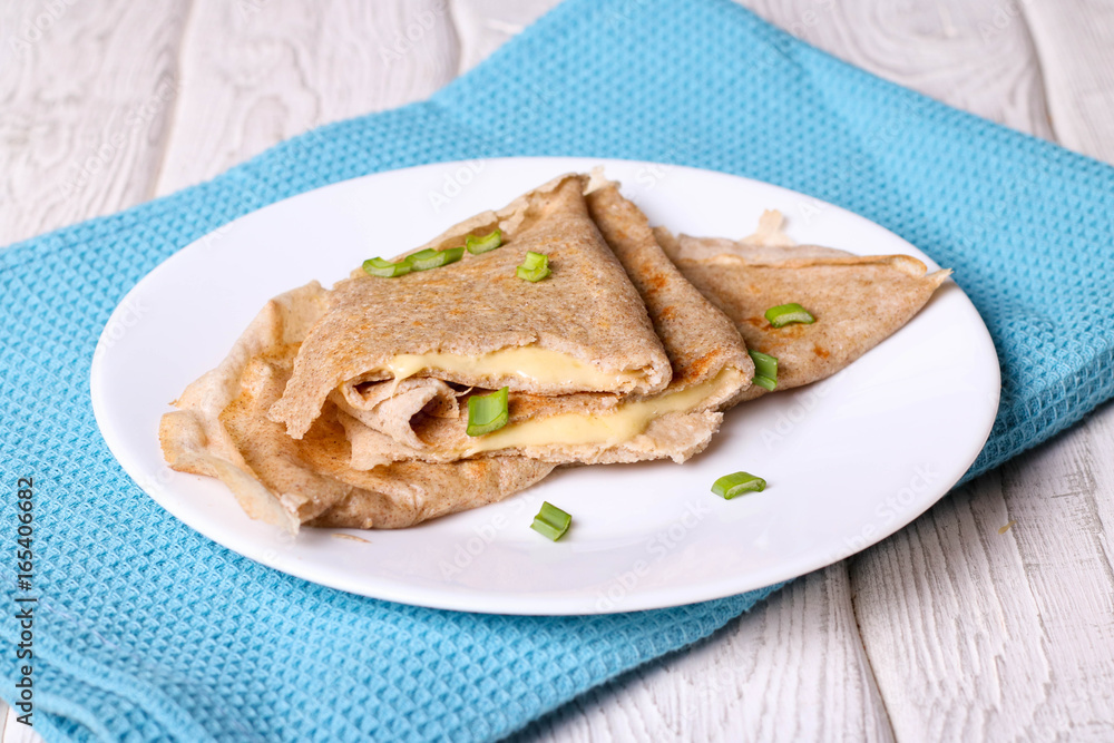 Two pancakes filled cheese with green onion on a white plate