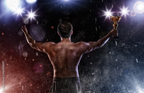 Back view of man fighter with trophy cup in hands, victory gesture