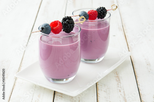 Healthy berry smoothie in glass on white wooden table
