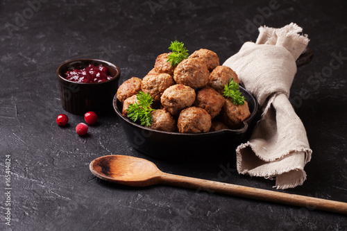 Traditional meatballs with cranberry sauce in a cast iron skillet