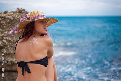 A young girl on a beach with a hat, sun and enjoys the sun, on the shoulder drawn sun from sun cream, summer, sun, sea