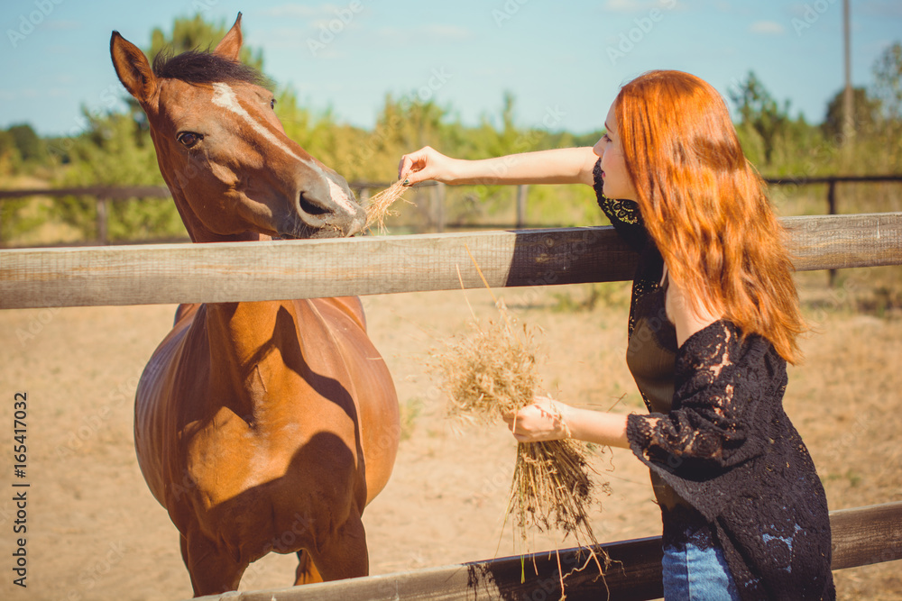Young beautiful woman with red hair wearing in casual Boho style, with  horses on a farm, pets animals in village in a rancho. Horses are human  friends Stock Photo | Adobe Stock
