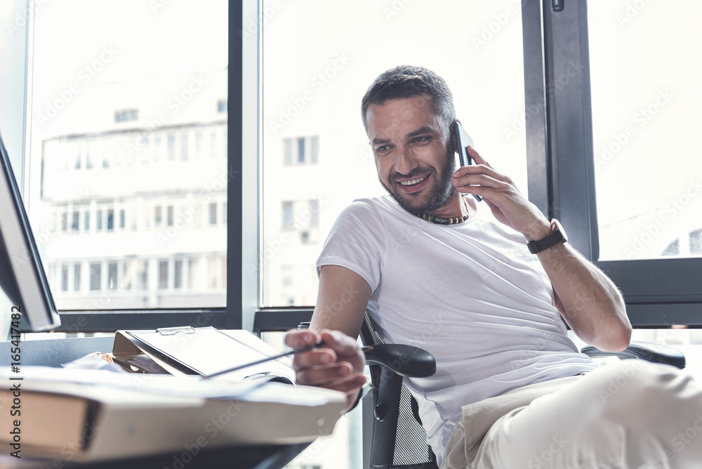 Fototapeta premium Cheerful mature man is talking on smartphone with pleasure
