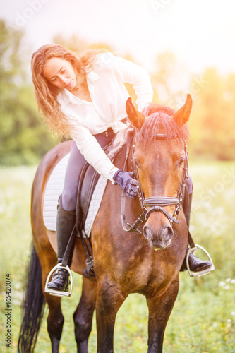 Young rider girl bent toward horse for complimenting it