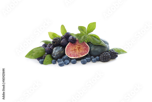Group of fresh fruits and berries with basil's on a white background. Ripe blueberries, blackberries, grapes, plums and figs. Blue and purple food. Fruits with copy space for text.