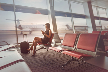 Happy charming lady is sitting on bench at airport