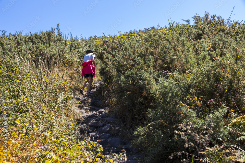 Woman walks the trail leading to the top of Monte do Facho in Cangas, Galicia, Spain