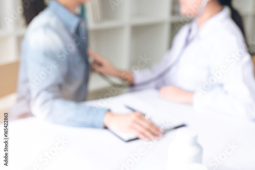Blurred background of Female doctor using a stethoscope to listen to women patient's chest checking heartbeat or lung in medical clinic, Physical examination, Medical and health care concept
