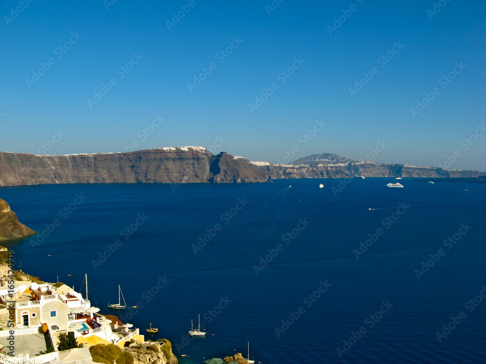 Fototapeta premium Santorini volcano caldera lit by afternoon sunshine, view from Oia, Santorini island, Cyclades, Greece