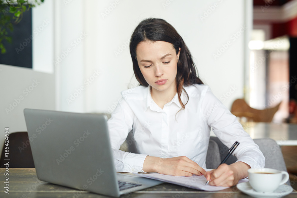 Young businesswoman signing papers and networking in cafe