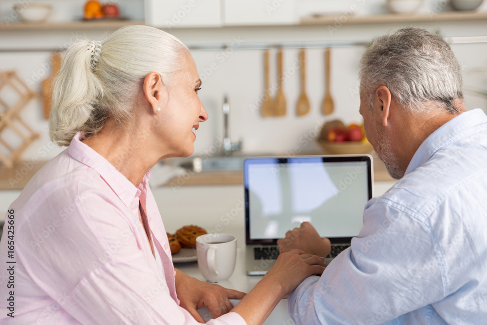 Fototapeta premium Happy mature loving couple family at the kitchen using laptop