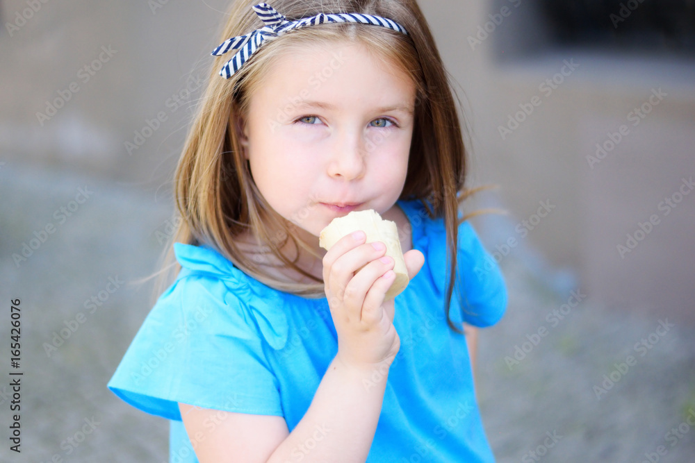 Adorable little girl eating tasty ice cream at park on warm sunny summer day Adorable little girl eating tasty ice cream at park on warm sunny summer day