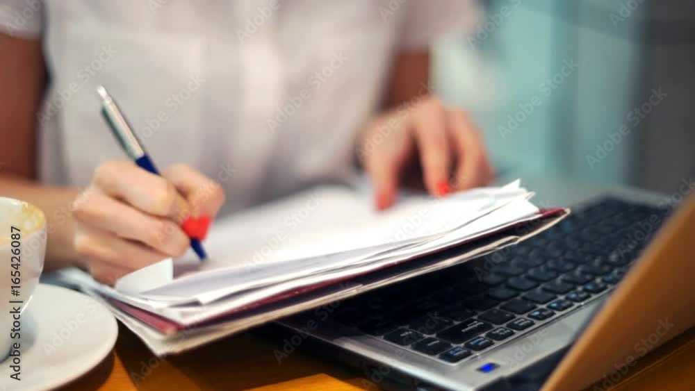 Businesswoman writing notes in documents sitting in cafe
Businesswoman writing notes in documents sitting in cafe