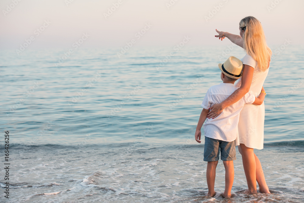 Family walking on the evening beach during sunset.Mother and son enjoy views of the sea. Family walking on the evening beach during sunset.Mother and son enjoy views of the sea.