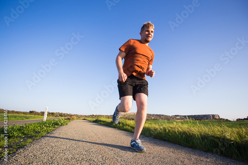 Man running outdoor sprinting for success. Male fitness runner sport athlete in sprint at great speed in beautiful landscape