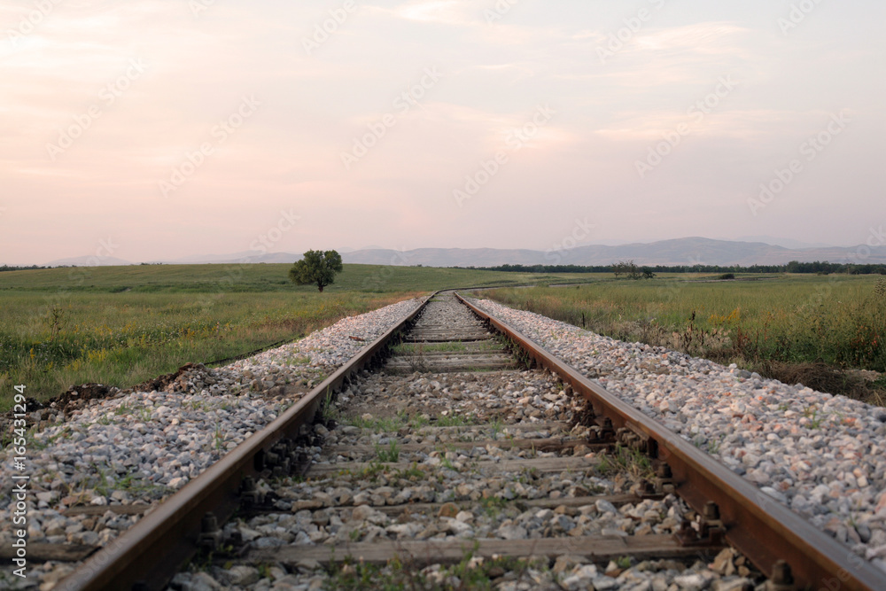 Train track in the field; travel, nature and infrastructure concept.