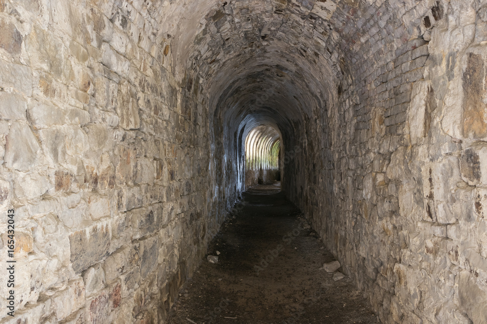 Fototapeta premium Spojrzenie w ciemny korytarz Cytadeli Namur. Na końcu jest odbicie światła przechodzącego przez luki, które nie są widoczne