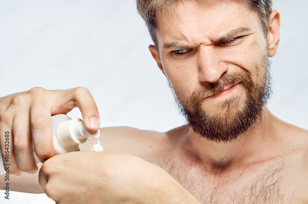 Obraz premium Man with a beard on white isolated background applies cosmetic cream