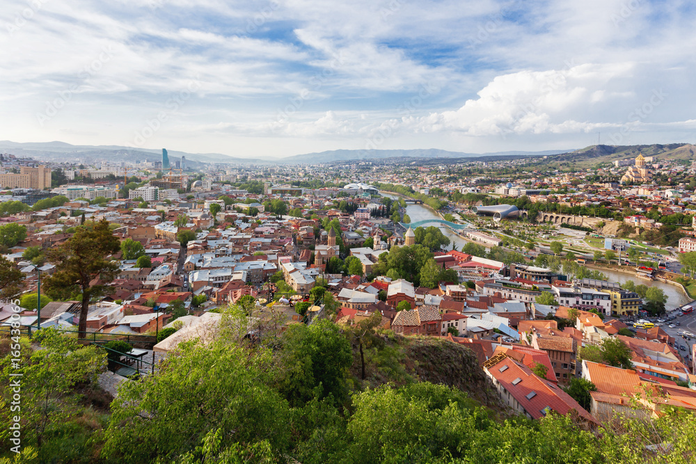 Fototapeta premium Panorama view of Tbilisi, capital of Georgia country. View from Narikala fortress. Cable road above tiled roofs.