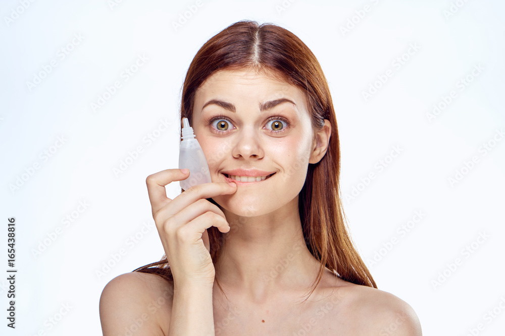 Young beautiful woman on white isolated background holds drops for eyes Young beautiful woman on white isolated background holds drops for eyes