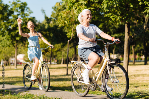 Cheerful senior woman riding bicycles with her granddaughter