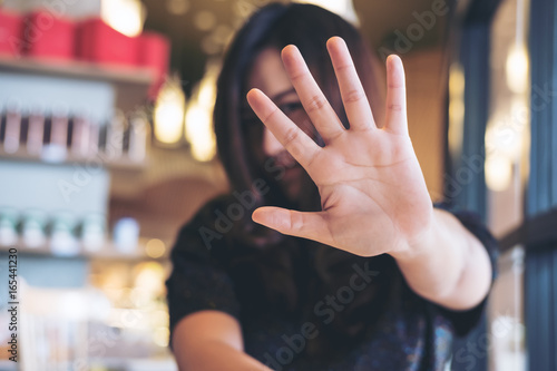 Fotografie An Asian woman showing her hand sign cover her face to say no to someone with fe