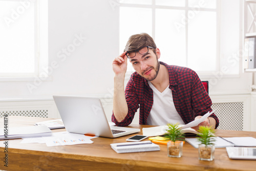 Young relaxed businessman with laptop in modern white office